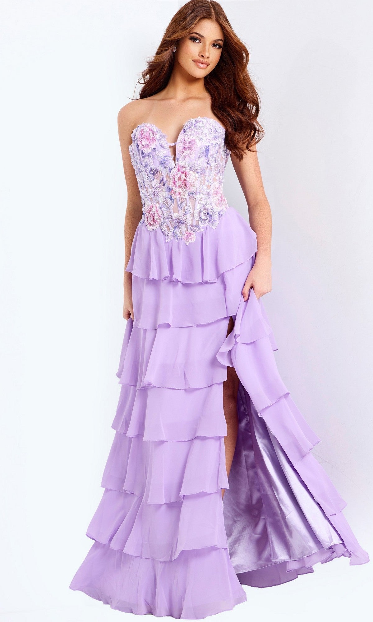 A woman wearing the Jovani 49628 long prom dress in lilac, featuring a strapless design, floral embroidery on the bodice, and a ruffle-layered chiffon skirt with a thigh-high slit.